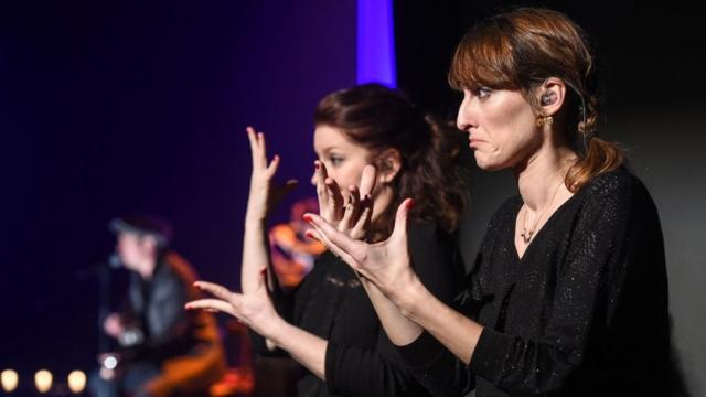Переводчики расшифровывают выступление певца на языке жестов на фестивале в Сосайме, Франция, 23 марта 2017 года