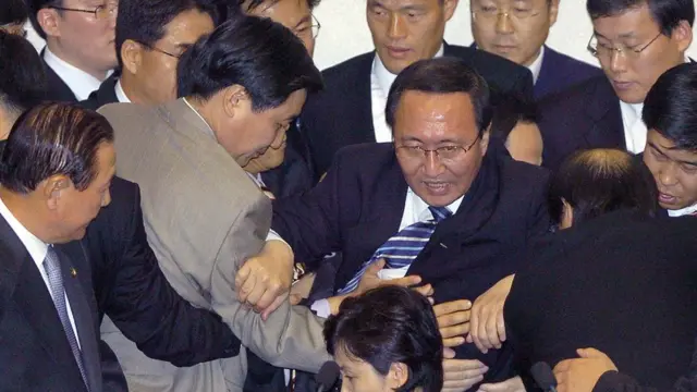 2005년 노회찬 당시 민주노동당 의원이 국회의 쌀 시장 개방에 항의하며 몸싸움을 벌이고 있다