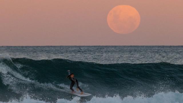 Una surfista en Sídney, Australia a la luz de la luna de sangre.