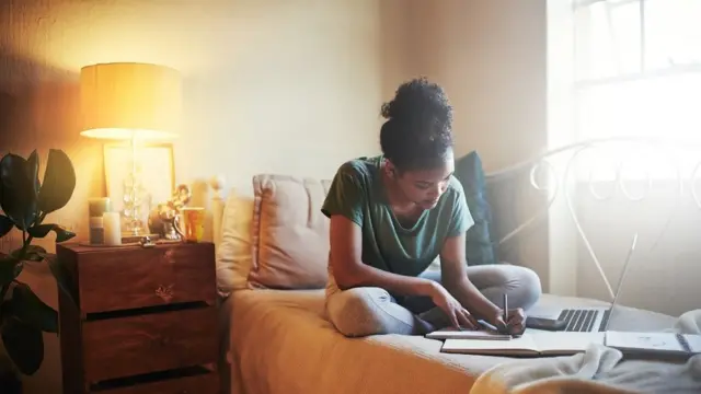 Mulher jovem estudando na cama