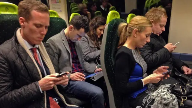 Personas viendo sus teléfonos mientras viajan en un tren