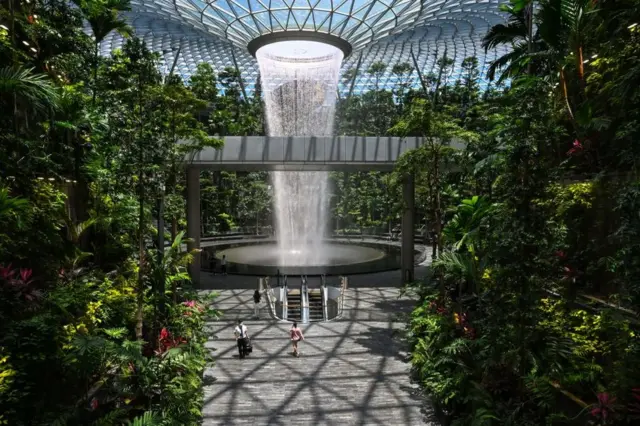 People walk past the Rain Vortex indoor waterfall feature at Jewel Changi Airport in Singapore on August 19, 2021.