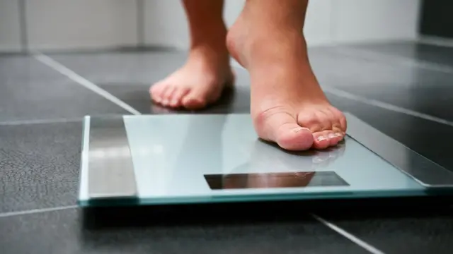 Mujer pesándose en báscula.
