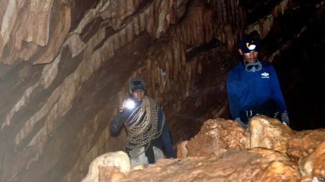 Rescue workers uses torches in their search for a football team trapped in a Thai cave