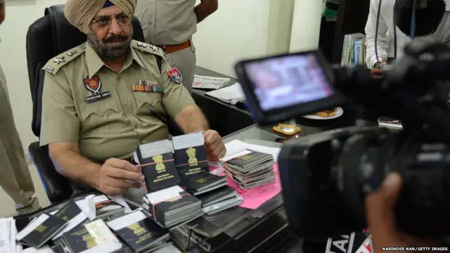 ndian Senior Superintendent of Police, Manmohan Singh (L)displays 75 passports and fake work visas for Singapore during a press conference in Amritsar on June 25, 2013