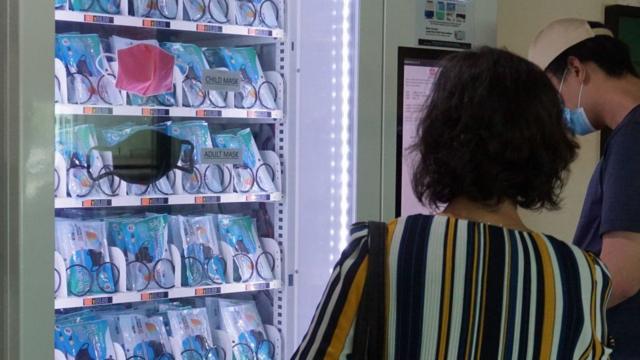 新加坡的一男一女在看著自動販賣機中的口罩。