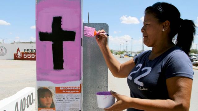 Una mujer pinta una cruz como parte de una campaña contra el feminicidio en Ciudad Juárez.