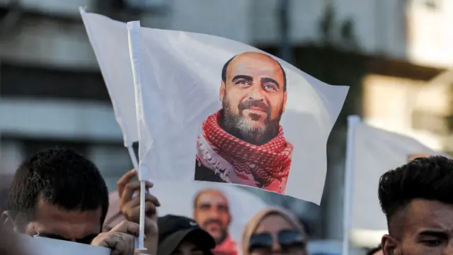 متظاهرون يرفعون صور الناشط الفلسطيني الراحل نزار بنات، أثناء مسيرة في مدينة الخليل بالضفة الغربية، 13 يوليو/تموز 2021