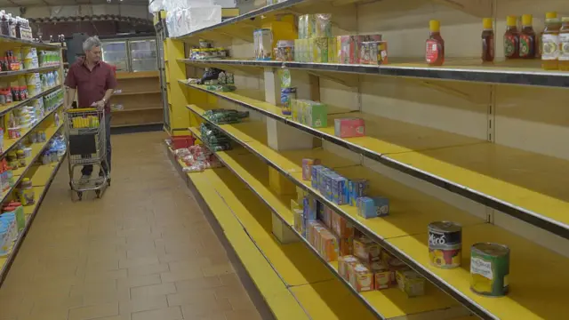 کمبود کالا در ونزوئلا؛ خریداری که در میان قفسههای نیمه خالی سوپرمارکت قدم میزند