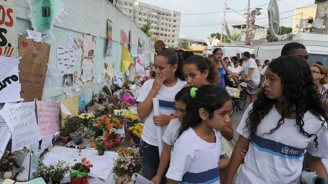 Des écolières pleurent en passant devant les messages et les fleurs laissés pour les victimes de l'attaque de Realengo en avril 2011.