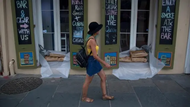 Una mujer pasa frente a tiendas en el Barrio Francés de Nueva Orleans que tienen sacos de arena en preparación para la tormenta tropical Barry.