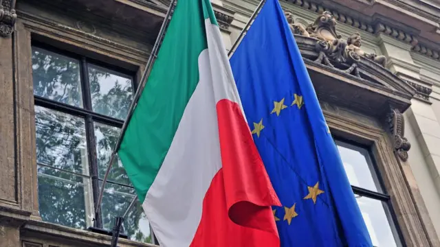 Bandeiras da Itália e da União Europeia na frente de um prédio