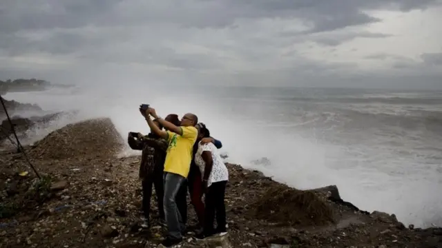 Raia wa Jamaica wapiga picha ufuoni, wakitazama mawimbi yanayosababishwa na Kimbunga Mathew, viungani mwa Kingston.