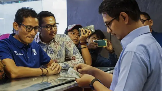 Bakal calon Wakil Presiden Sandiaga Uno (kiri) menukarkan uang dolar AS ke mata uang rupiah di Jakarta, Kamis (6/9). Sandiaga Uno menukarkan sebagian dolar AS miliknya sebagai upaya untuk menjaga nilai mata uang rupiah.