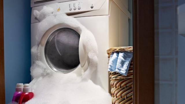 Máquina de lavar roupa com espuma saindo pela abertura frontal