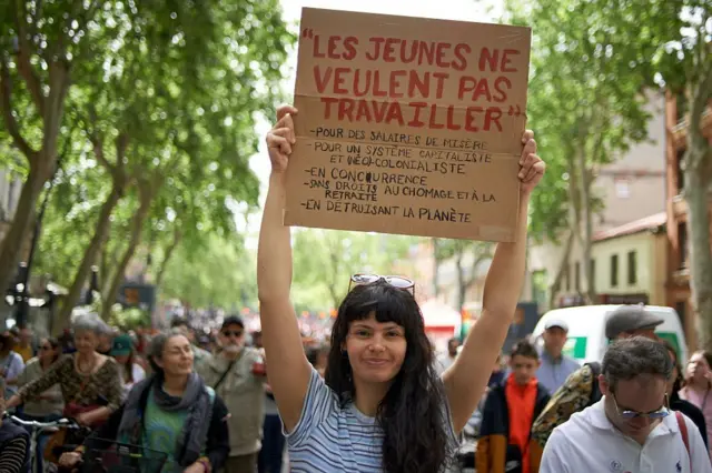 د یوې ځوانې ښځې په لاسونو کې یوه دړه ده، چې پرې لیکلي: ''ځوانان نه غواړي د یوه پانګوال او نوي استعماري سیسټم لپاره، چې د بې کارۍ او تقاعد هېڅ حق په کې نه شته یوازې د لوږې د لېرې کولو تنخا لپاره کار وکړي. او ځمکه له خځلو ډکه کړي.'' 