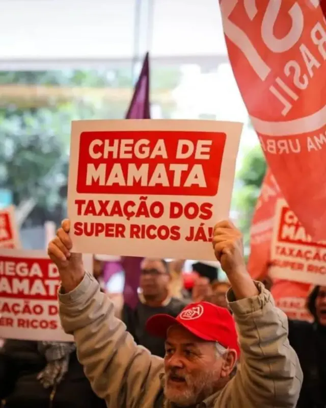 Protesto na sede do Itaú em SP pede taxação de super-ricos: o que diz projeto do governo Lula Homem segura cartaz com a frase "chega de mamata, taxação dos super ricos já"