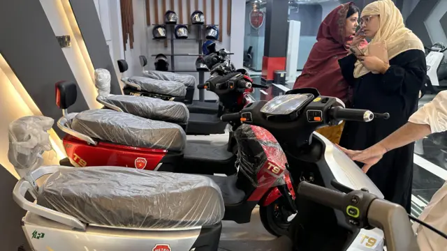 Женщины рассматривают электромопеды в пакистанском автосалоне