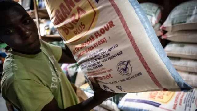 Un homme tenant un sac de farine de blé dans un magasin de stockage