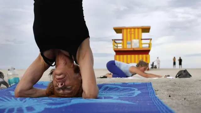 Женщина занимается йогой на пляже.