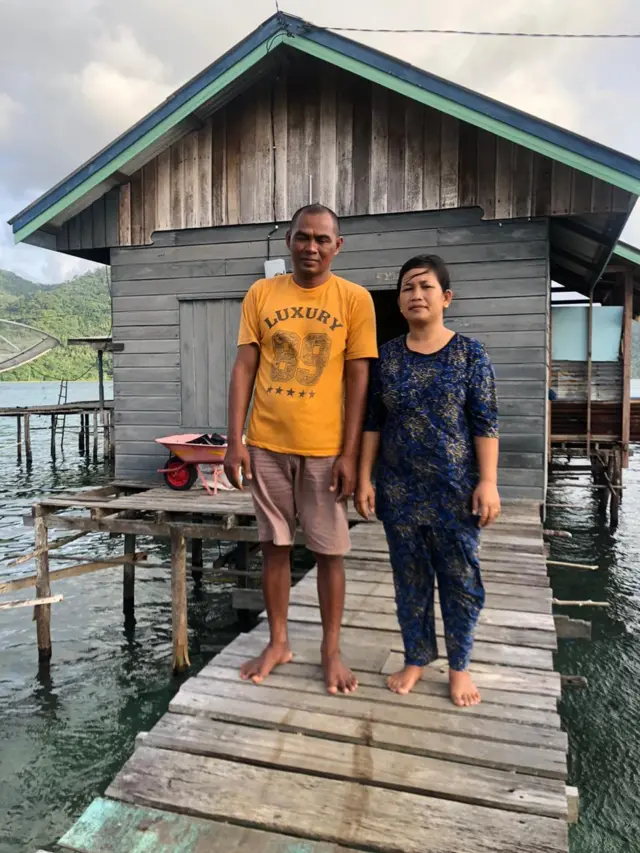 Hafis dan Bariah berdiri di depan rumahnya di Pulau Tiga Barat.