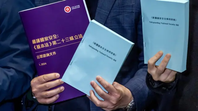 香港立法会大楼内议员举起“23条”国安立法草案文本与咨询文件让媒体记者拍照(8/3/2024)