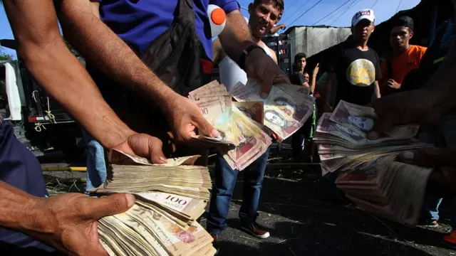 Hombres con billetes de 100 bolívares.