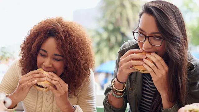 Duas mulheres comendo hambúrgueres