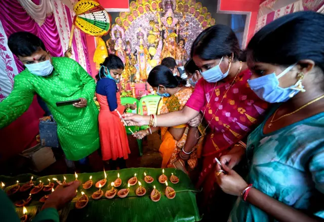 সন্ধি পূজার আয়োজনে আলো জ্বালানো হচ্ছে।
