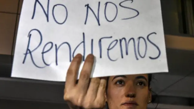 Joven con pancarta que dice "No nos rendiremos".
