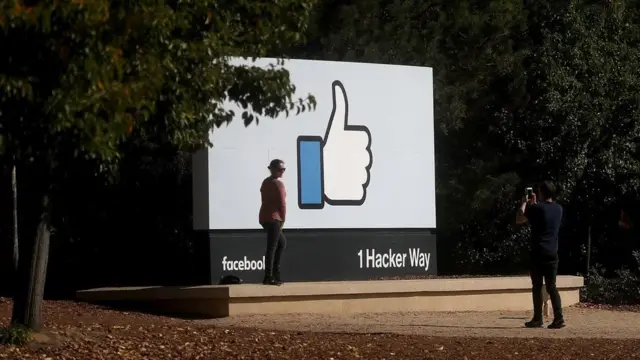 Жінка фотографується біля логотипу Facebook