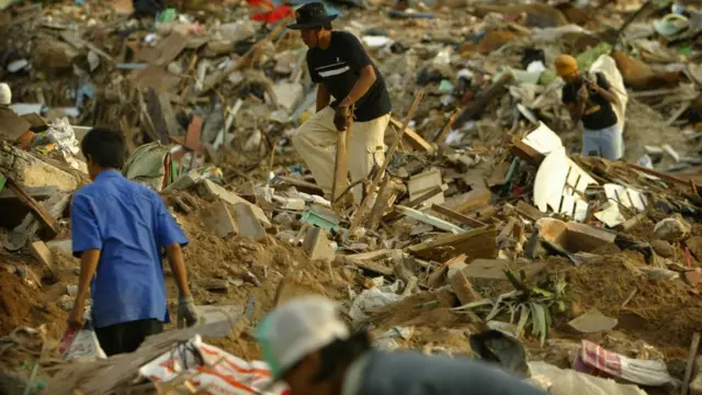 ผู้คนเก็บกวาดซากปรักหักพัง บนหาดป่าตอง