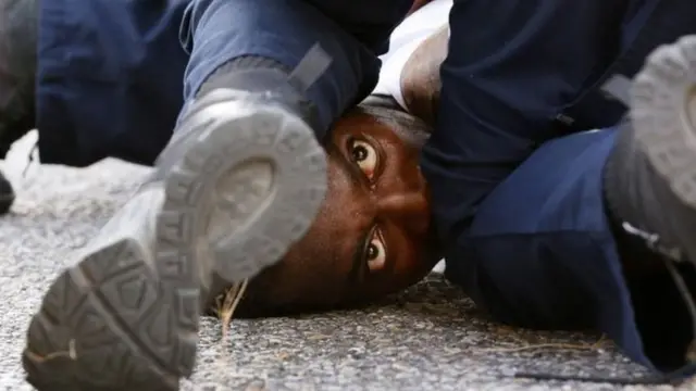 Iyi foto yerekana umugabo atabwa muri yombi n'igipolisi