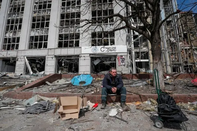 A resident looks on near a building destroyed in the course of the Ukraine-Russia conflict, in the southern port city of Mariupol, Ukraine April 10, 2022.
