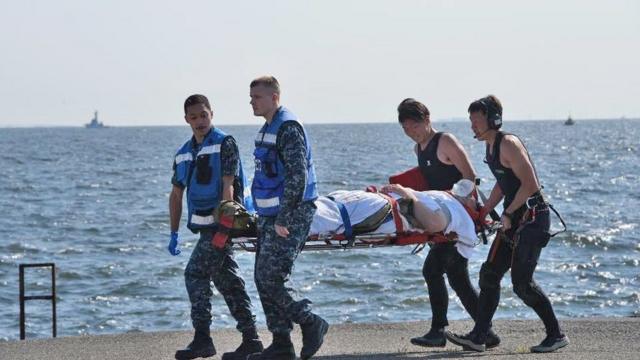 an injured USS Fitzgerald personnel being carried by US military personnel (L) and Japanese Maritime Self-Defense Force members (R)