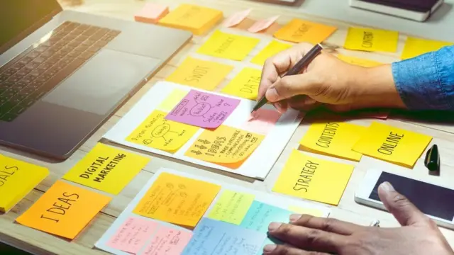 સ્ટીકી નૉટ્સ પર દરેક વિગત લખતી એક વ્યક્તિ