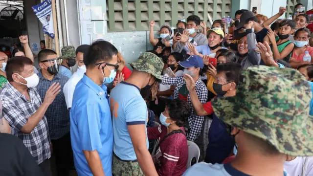 El presdiente Rodrigo Duterte (der. en camisa de cuadros) saluda a algunas de la vícitmas en la isla de Bohol, 17 de diciembre de 2021