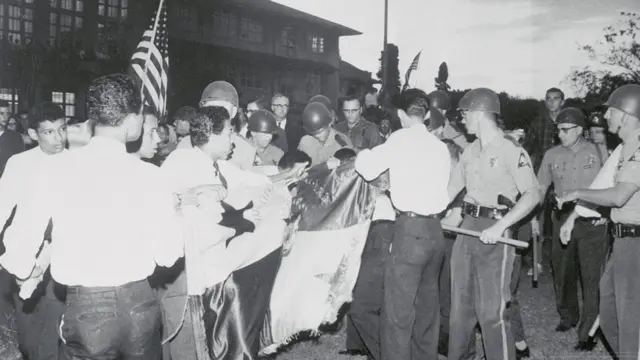 Estudiantes panameños frente a la policía zoneíta y rodeados de estadounidenses justo antes de que comenzaran los forcejeos para evitar que izaran su bandera.