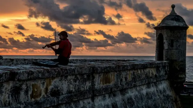 Un hombre disfrazado de payaso toca el violín en Cartagena de Indias