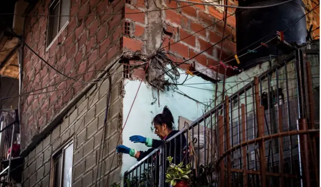 Une femme portant des gants fait des gestes aux voisins depuis son balcon dans le bidonville "Barrio 31" à Buenos Aires, en Argentine