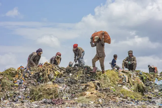 የቆሻሻ ክምር የሚያፀዱ ሰራተኞች የሚያሳይ ምስል።