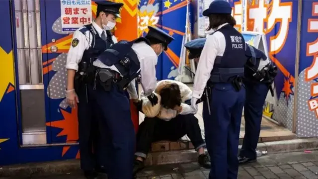 Kundi la maafisa wa polisi wakimhudumia mtu aliyekuwa amelewa barabarani.