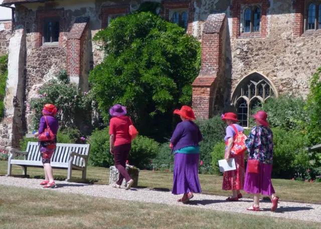 Un grupo de mujeres con sombre caminando hacia la iglesia