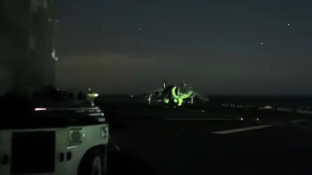 A Harrier jet fighter at night on the deck of USS Bataan preparing for take off