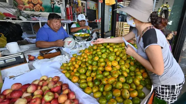 Mulher comprando frutashandicap apostas esportivasfeira livre