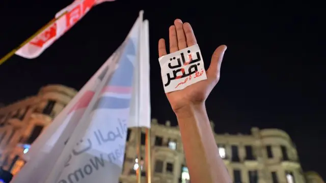 يد ولافتة مكتوب عليها "النساء خط أحمر"