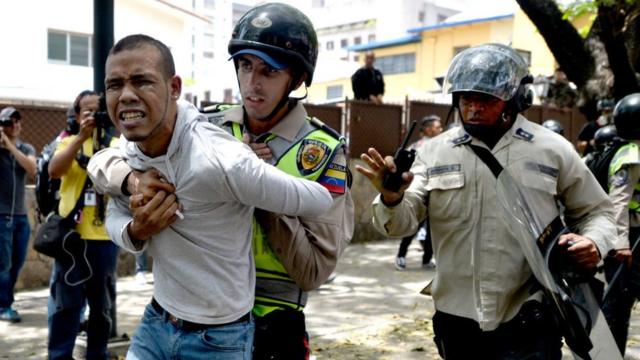 Un funcionario de la Policía Nacional Bolivariana detiene a un manifestante.