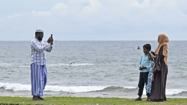 Un homme prend des photos avec un téléphone portable de sa famille lors de leur visite au Fort de Galle, à Galle