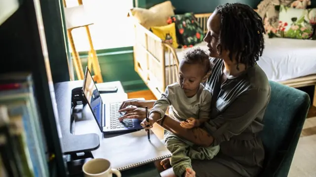 Mãe trabalhando com bebê no colo