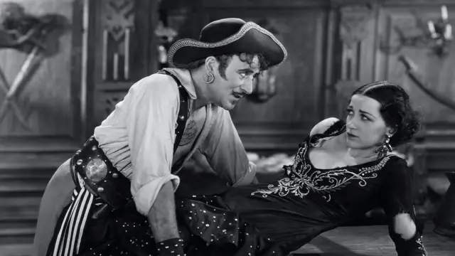 Une photo d'un film de pirates des années 1920 montrant un pirate masculin menaçant une femme